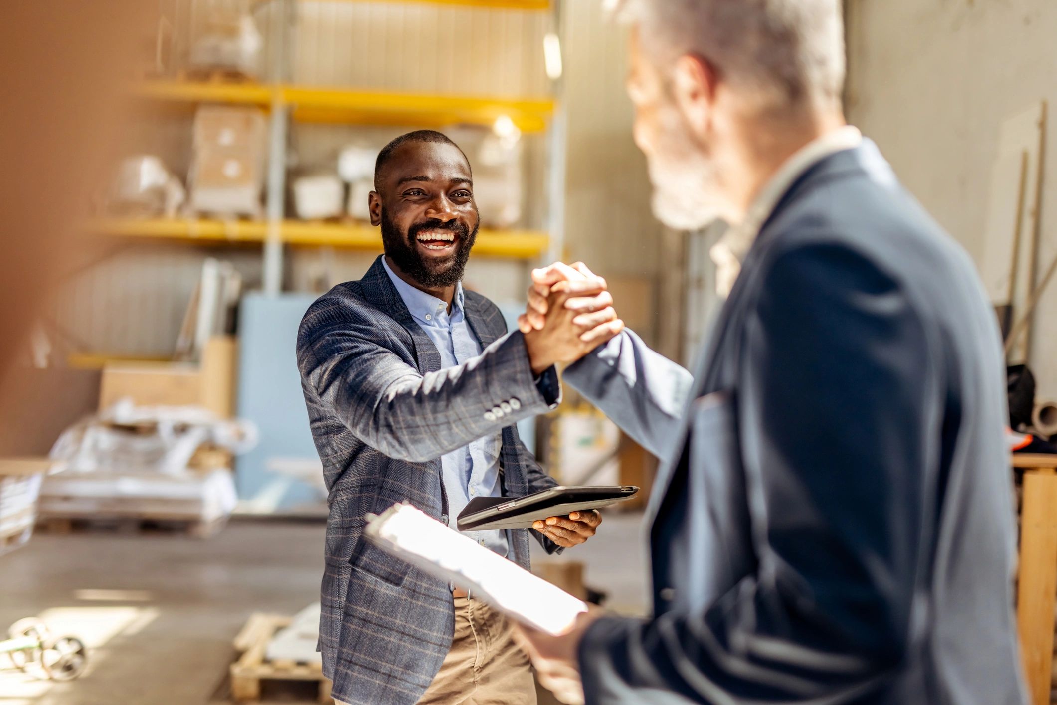 Two business professionals shaking hands in a bright work environment
